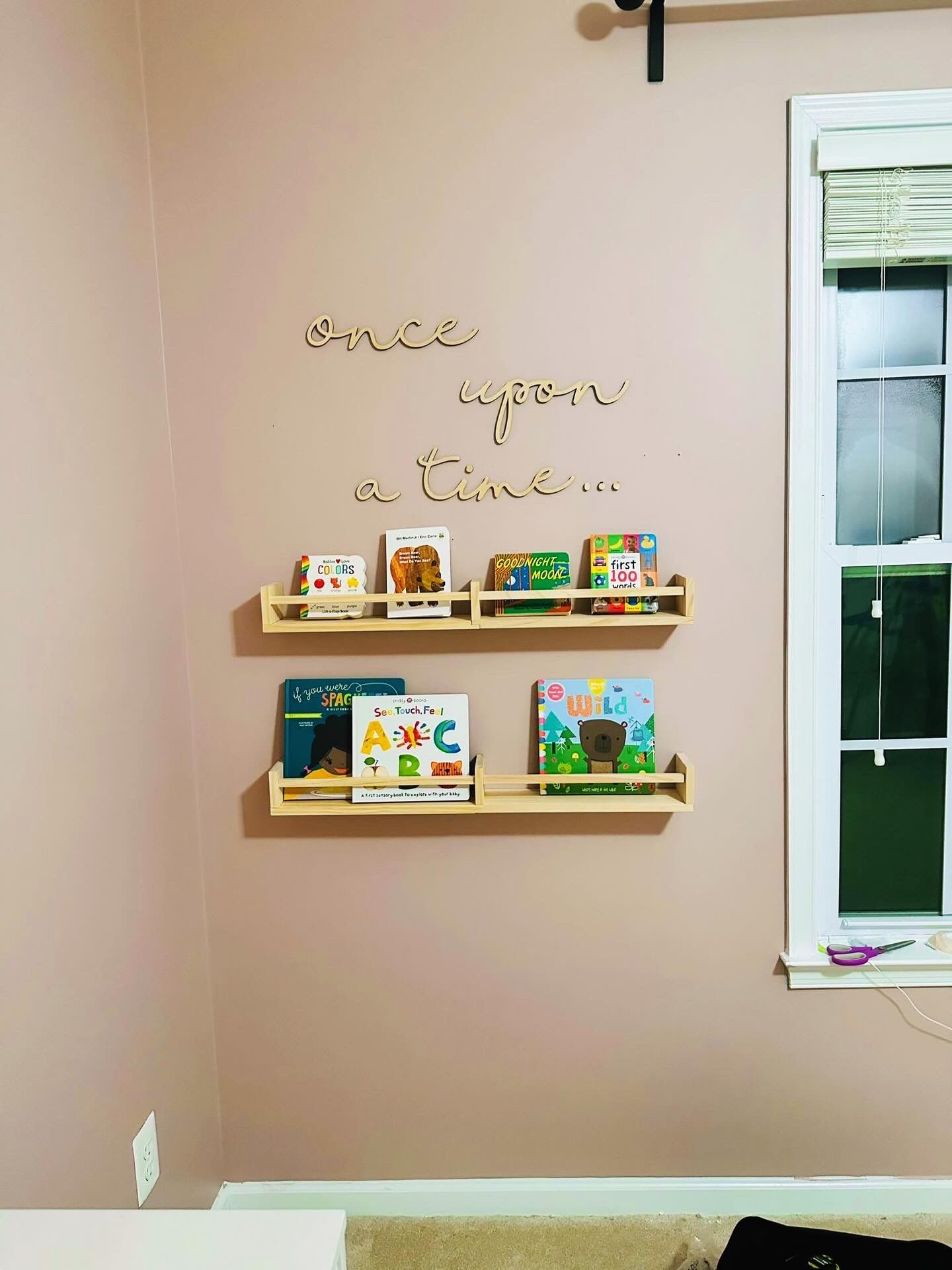 Soothing baby girls nursery with muted pink paint color and daisy decal accent wall designed by Pragya Saikia in South Riding, Virginia