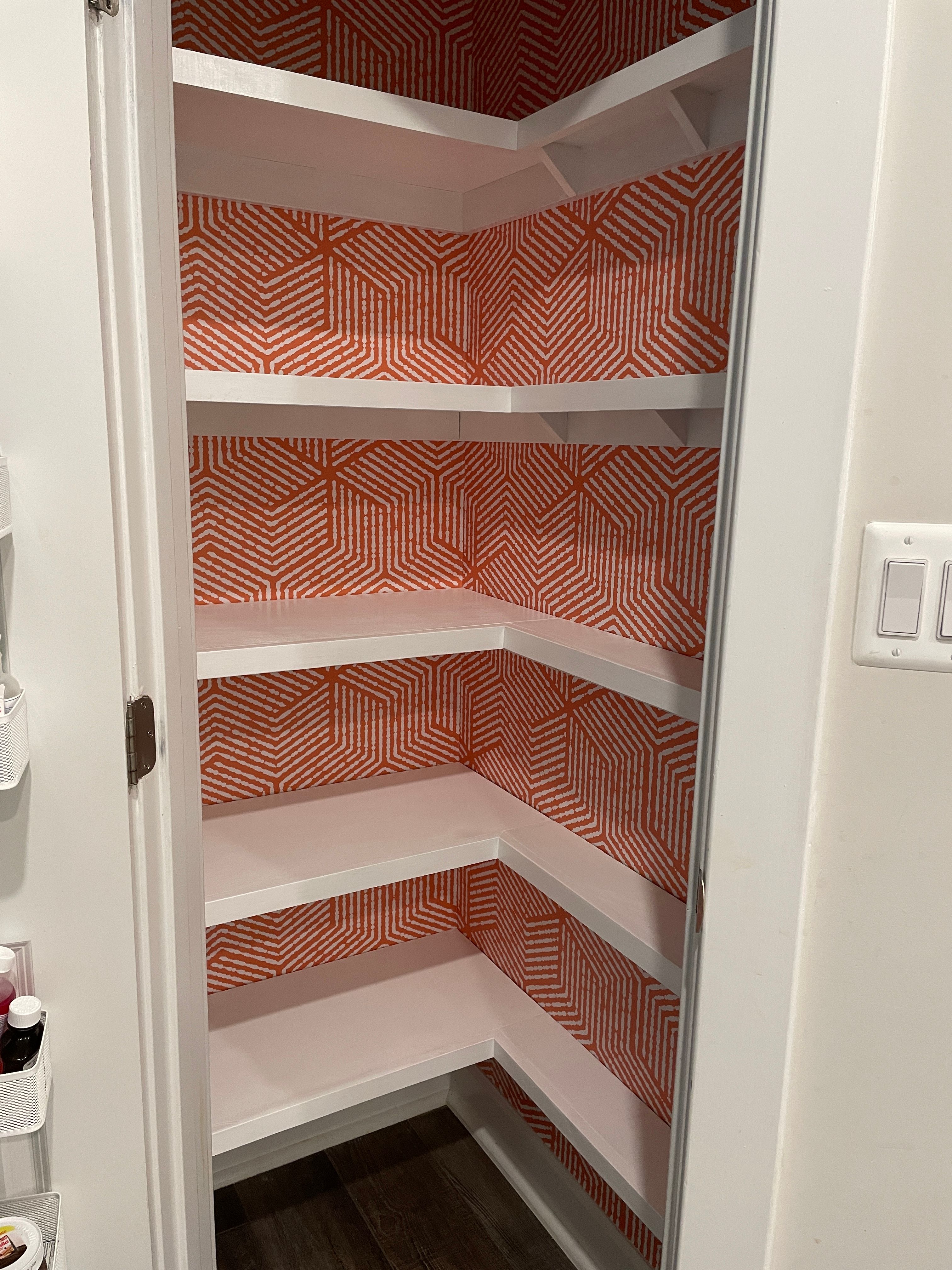 Small pantry remodel designed with colorful wallpaper and white shelves by Pragya Saikia Design in Reston, Virginia